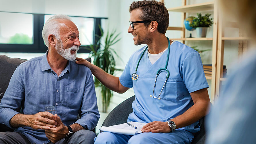 A healthcare professional speaks with an older man, providing guidance and support in a medical environment.